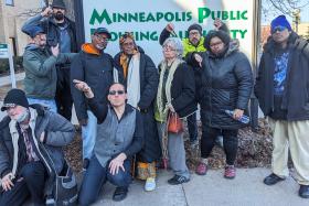 A group people gathered in front of the Minneapolis Public Housing Authority building, looking frustrated