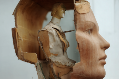 a small broken mannequin sitting inside the head of a larger broken mannequin