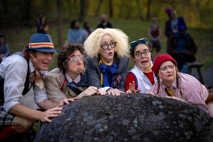 Performers from Big World hide behind a rock