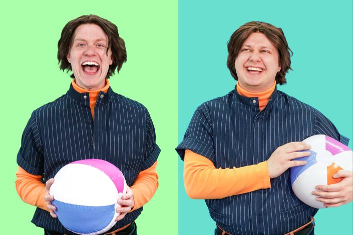 A set of twins stands side by side in matching outfits, holding matching beach balls