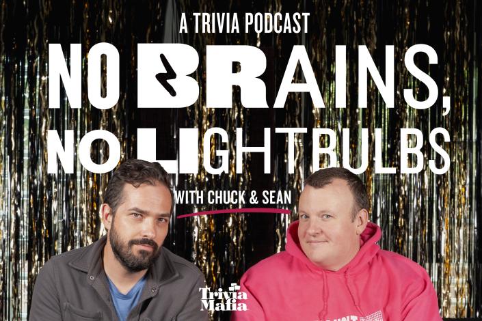 Two men, one wearing a grey collared jacket and blue t shirt, the other wearing a pink hoodie, both looking at the camera seated in front of a wall of reflective streamers; white text show title