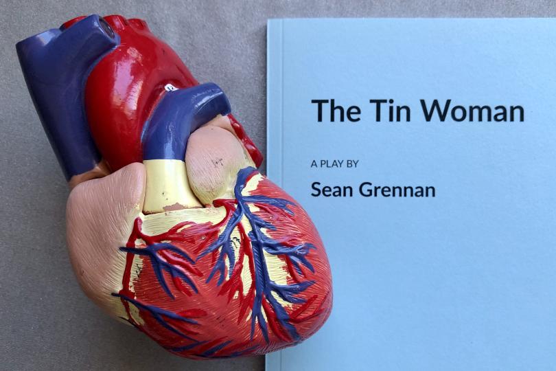 Model of a human heart atop a play script that reads The Tin Woman, A play by Sean Grennan