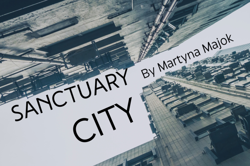 Show poster "Sanctuary City by Martyna Mojak" looking up a grey building.