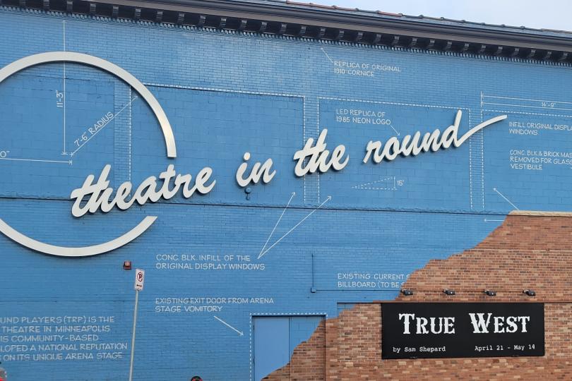 Front of Theatre in the Round. A blue facade with a mural representing blueprints across it.
